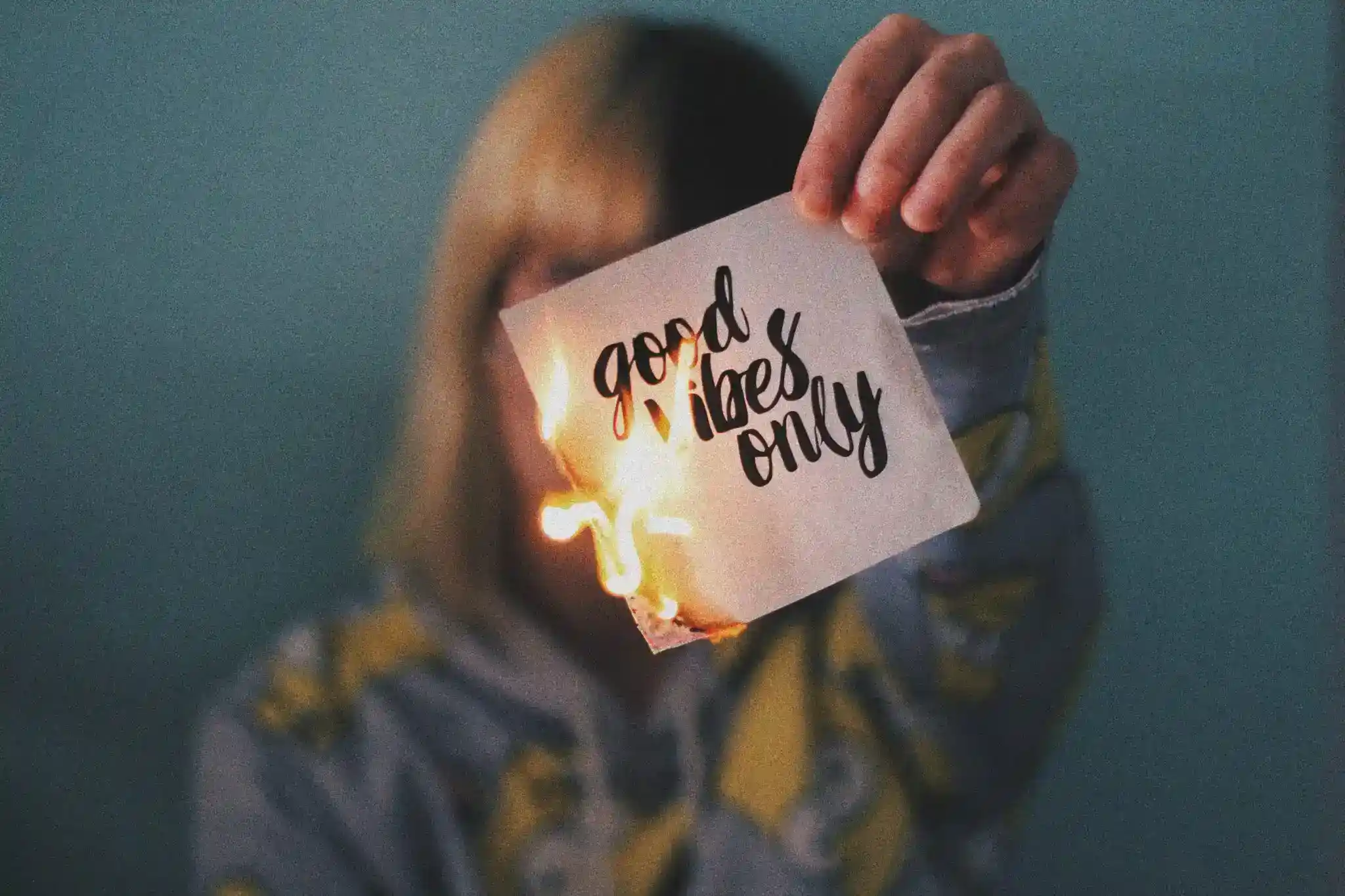 woman holding burning piece of paper with text saying good vibes only