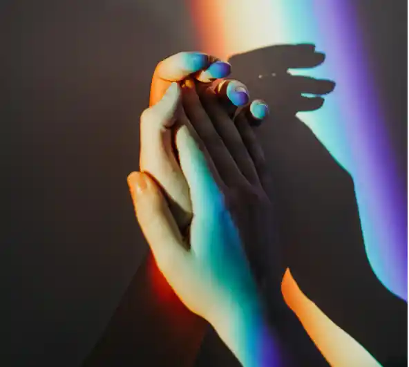 two hands holding in different coloured lights