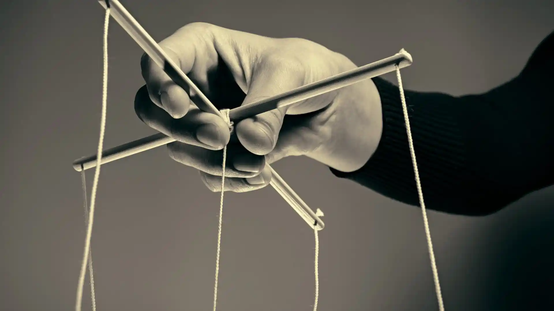 hand holding stick attached to ropes for puppet