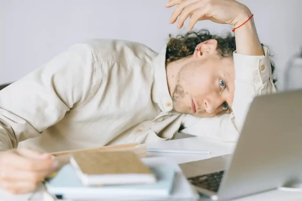 man in front of laptop lying with head on arm burnout