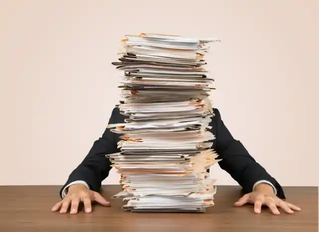 person sitting behind a stack of papers or documents