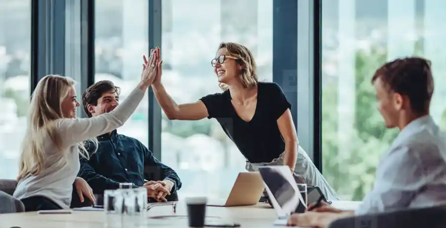 woman congratulating colleague in boardroom meeting