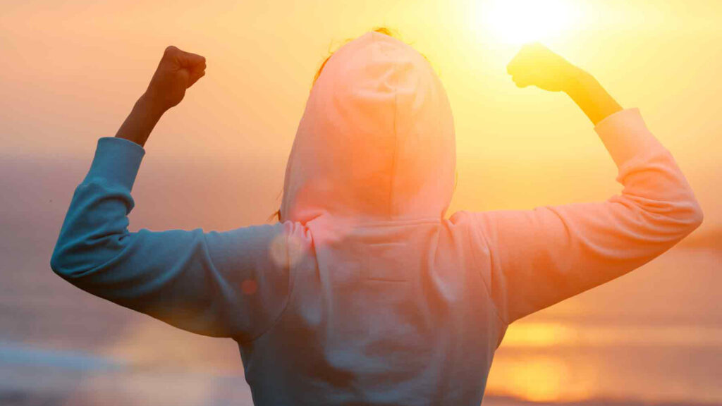 silhoutte of a person standing with arms up looking at the sunset