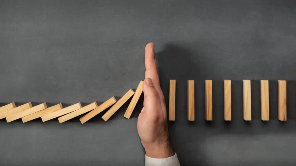 hand stppoing wooden dominoes from falling