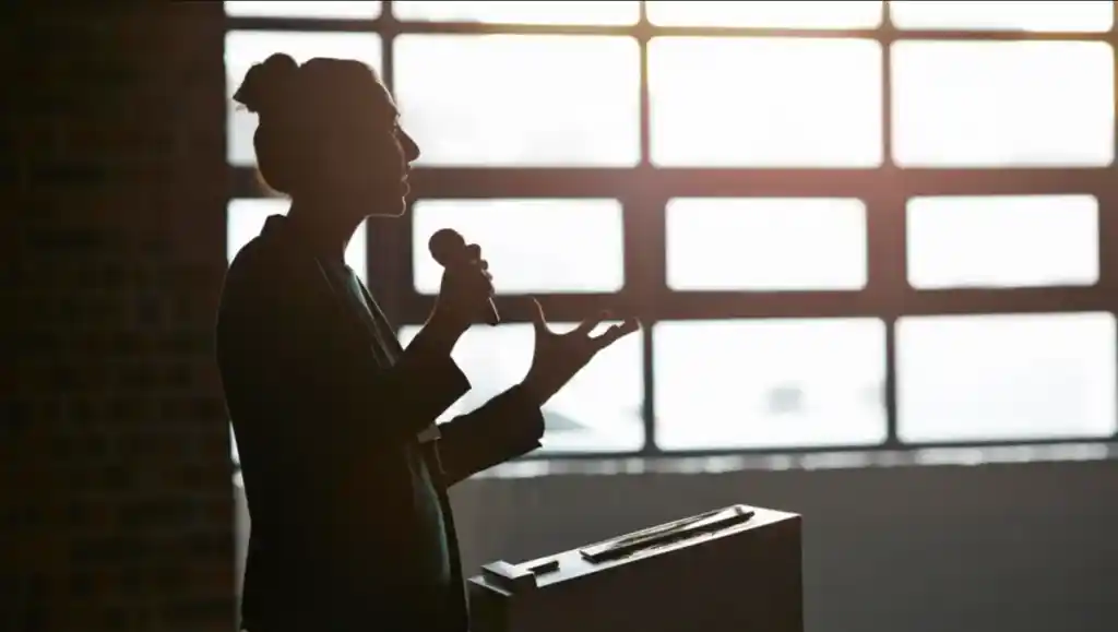 silhouette of woman speaking on a microphone - public speaking