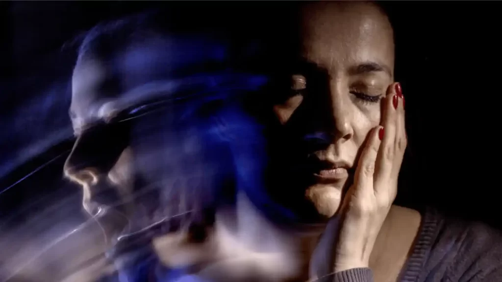 women with closed eyes and her left hand on her face