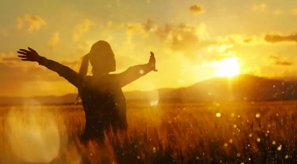 silhoute of a woman standing in the field at sunset with her arms stretched out