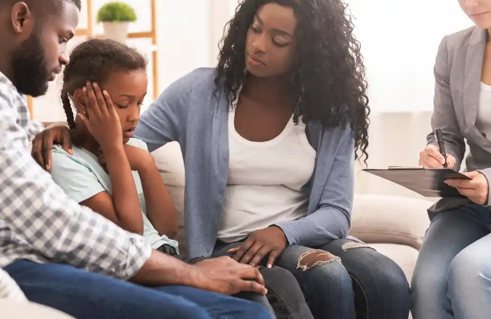 couple sitting on a couch with their child inbetween them in family therapy