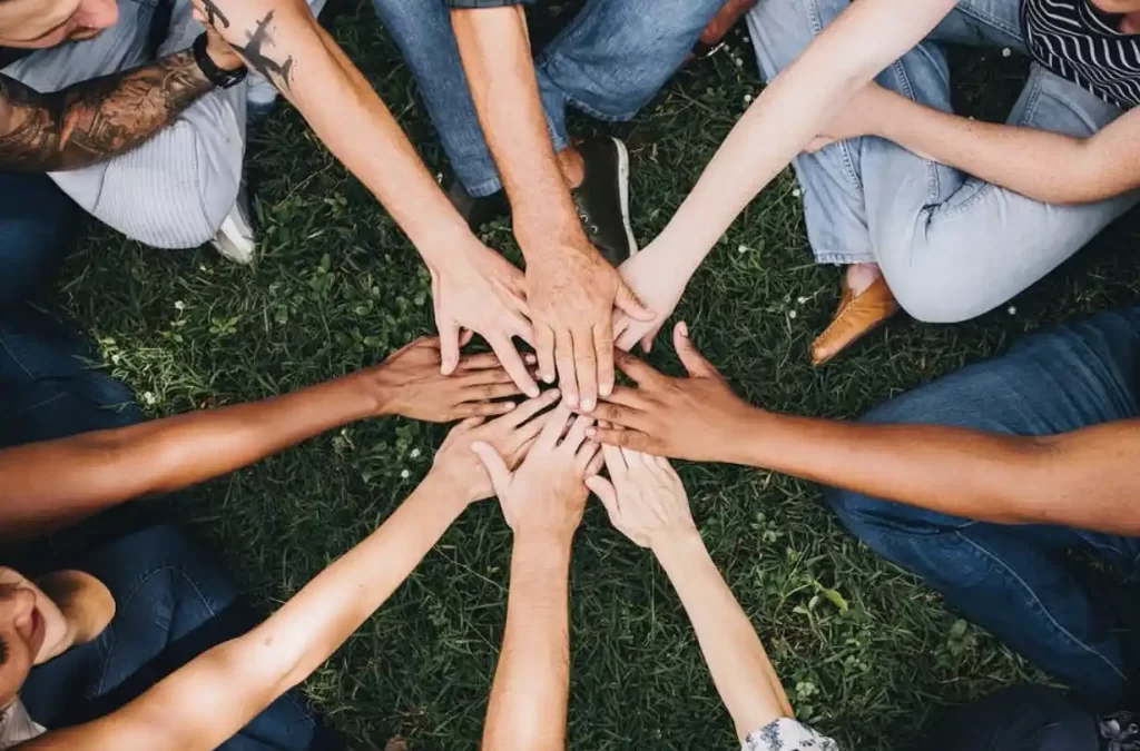 group of people in a circle putting their hands together in the middle