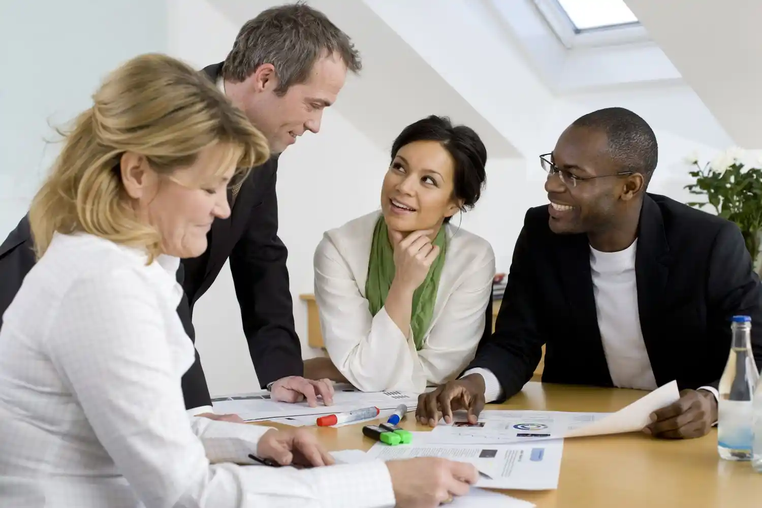 four people around a boardroom table having a meeting