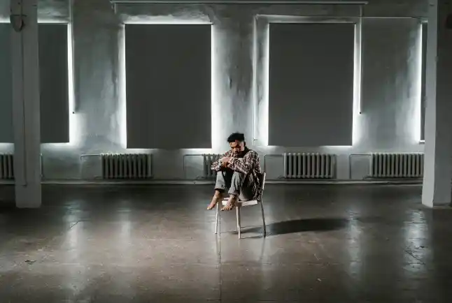man sitting alone on a chair in a big room