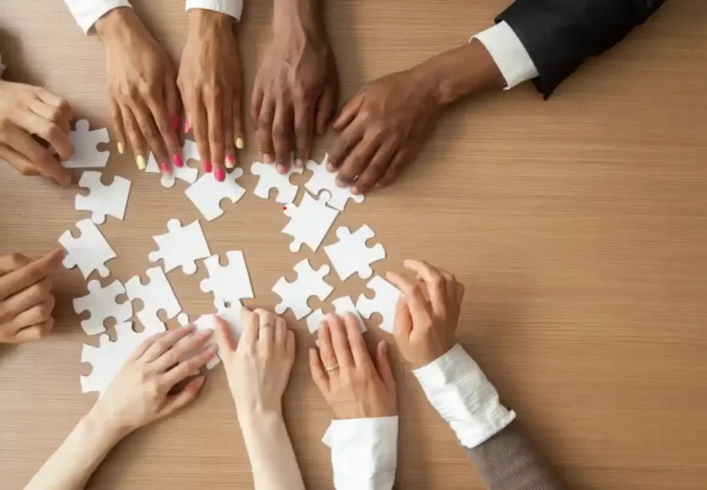 different sets of hands on a table with white puzzle pieces