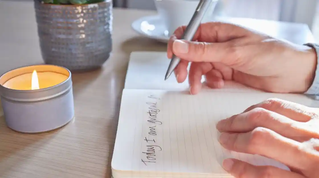 hands writing in a book "Today I am grateful for..."